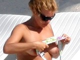 Billie Piper sunbathes topless on a beach