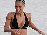 Michelle Hunziker in a tiny bikini top playing volleyball on the beach